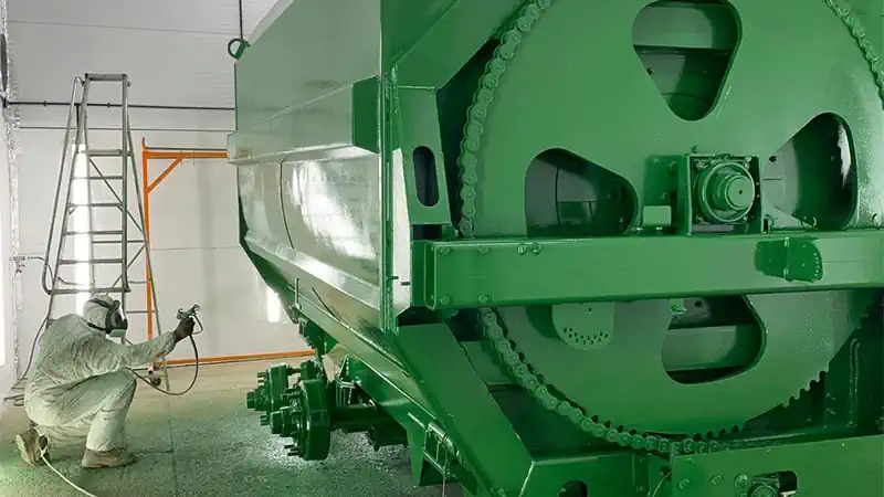 Fabrication Projects. Employee in full PPE Spray Painting Keenan Feeder.