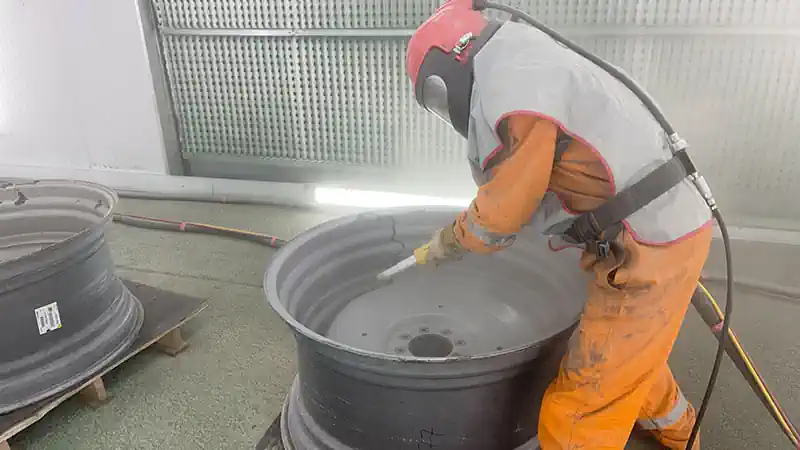 Shot Blasting Paint. Employee in Protective Equipment Shot Blasting Wheel.